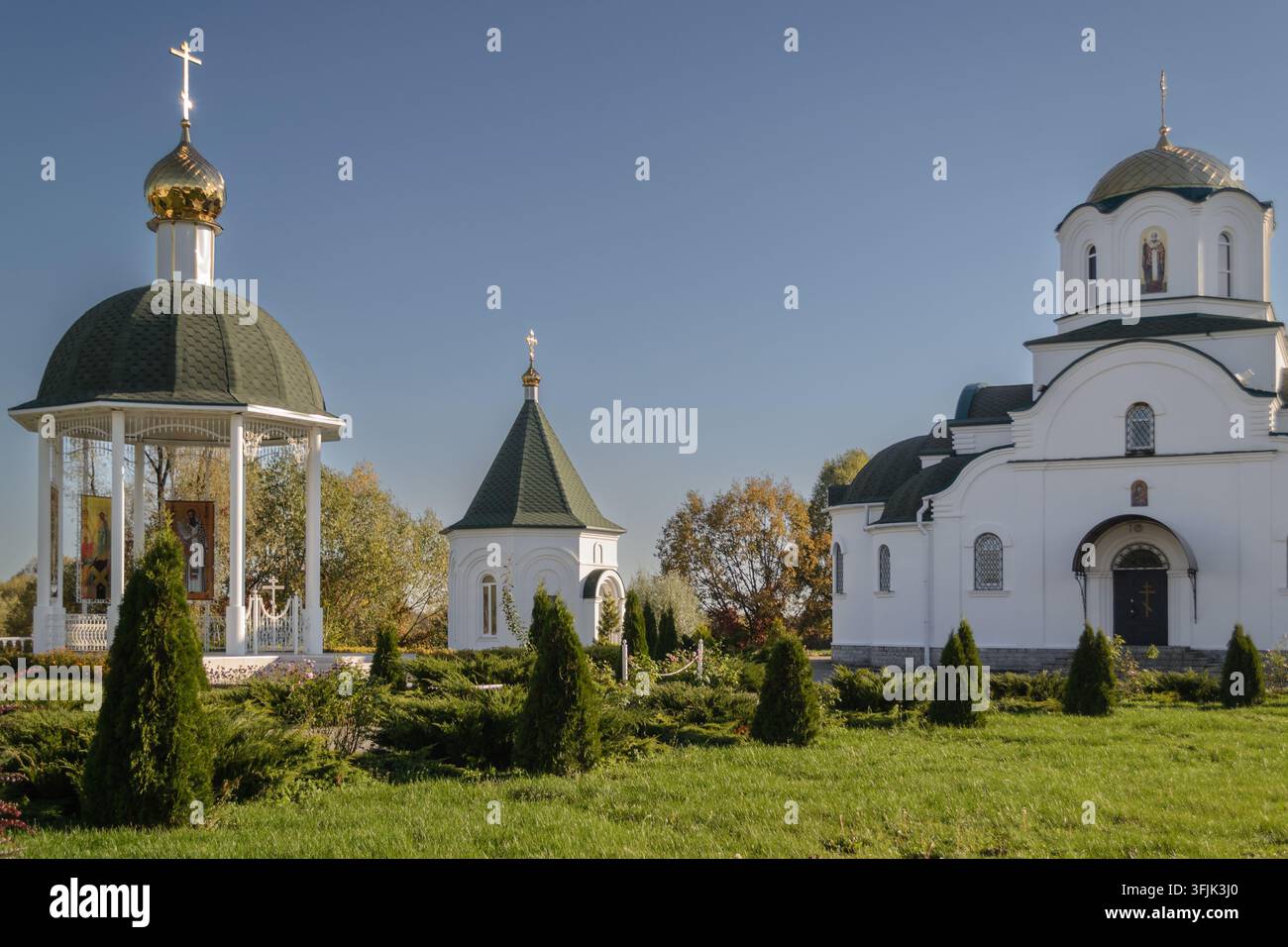 BARKOLABOVO, BIELORUSSIA – 8 OTTOBRE 2021: Vista panoramica del complesso monastico ortodosso con una rotonda bianca, una cappella e una chiesa dietro un prato verde. Foto Stock