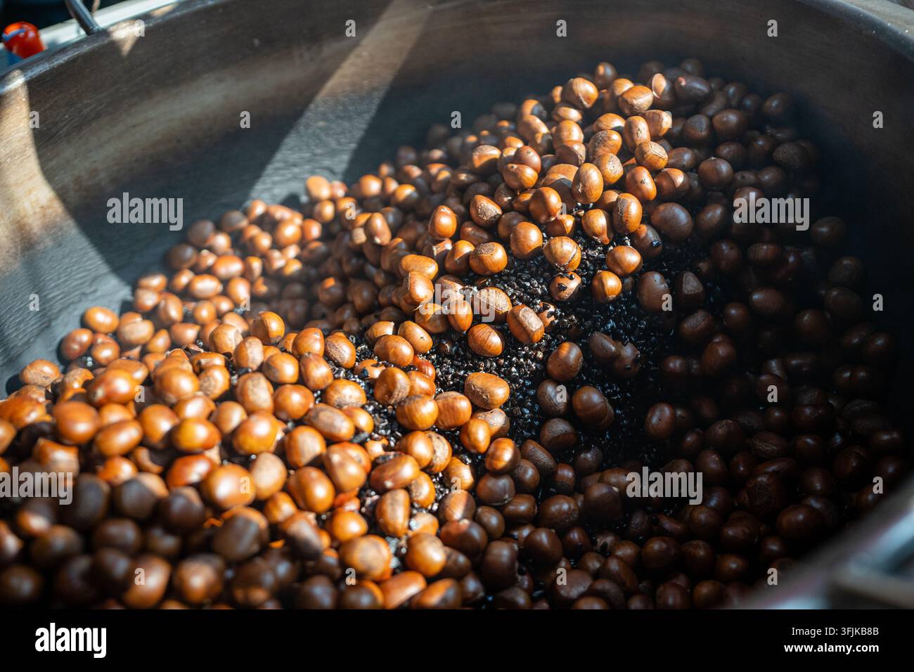 Mazzo di frutti di castagne arrostiti che cuociono in un grande wok in un mercato di strada a Bangkok, Thailandia. Foto Stock