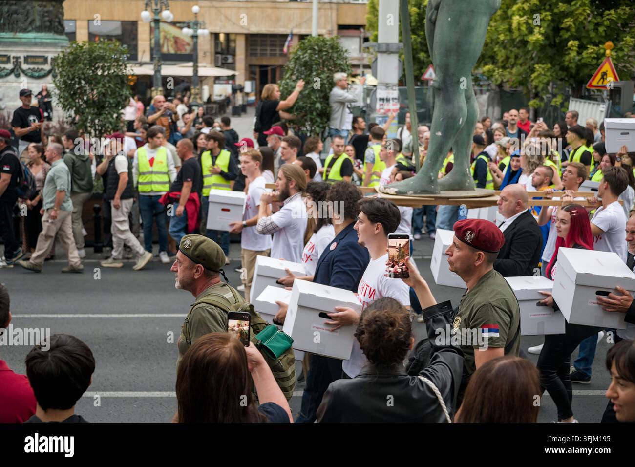 BELGRADO, SERBIA - 14 SETTEMBRE 2026: Veterani militari indossano uniformi e berretti mentre scortano attivisti studenti che portano scatole bianche per le firme. Foto Stock