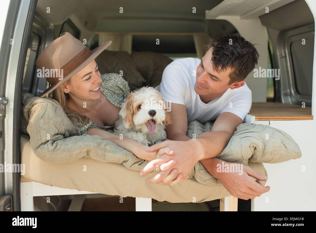 Coppia felice con il cane domestico sdraiata nel camper durante un viaggio su strada Foto Stock