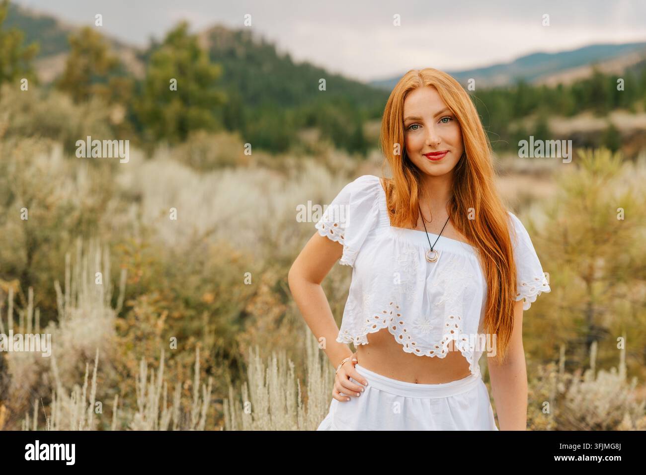 Giovane donna sicura di sé con lunghi capelli rossi che posa all'aperto Foto Stock