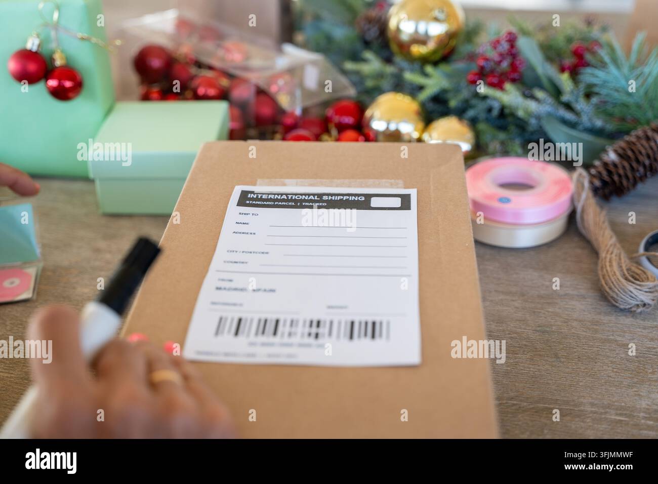 Scrittura a mano su un'etichetta del pacco per la consegna internazionale di Natale Foto Stock