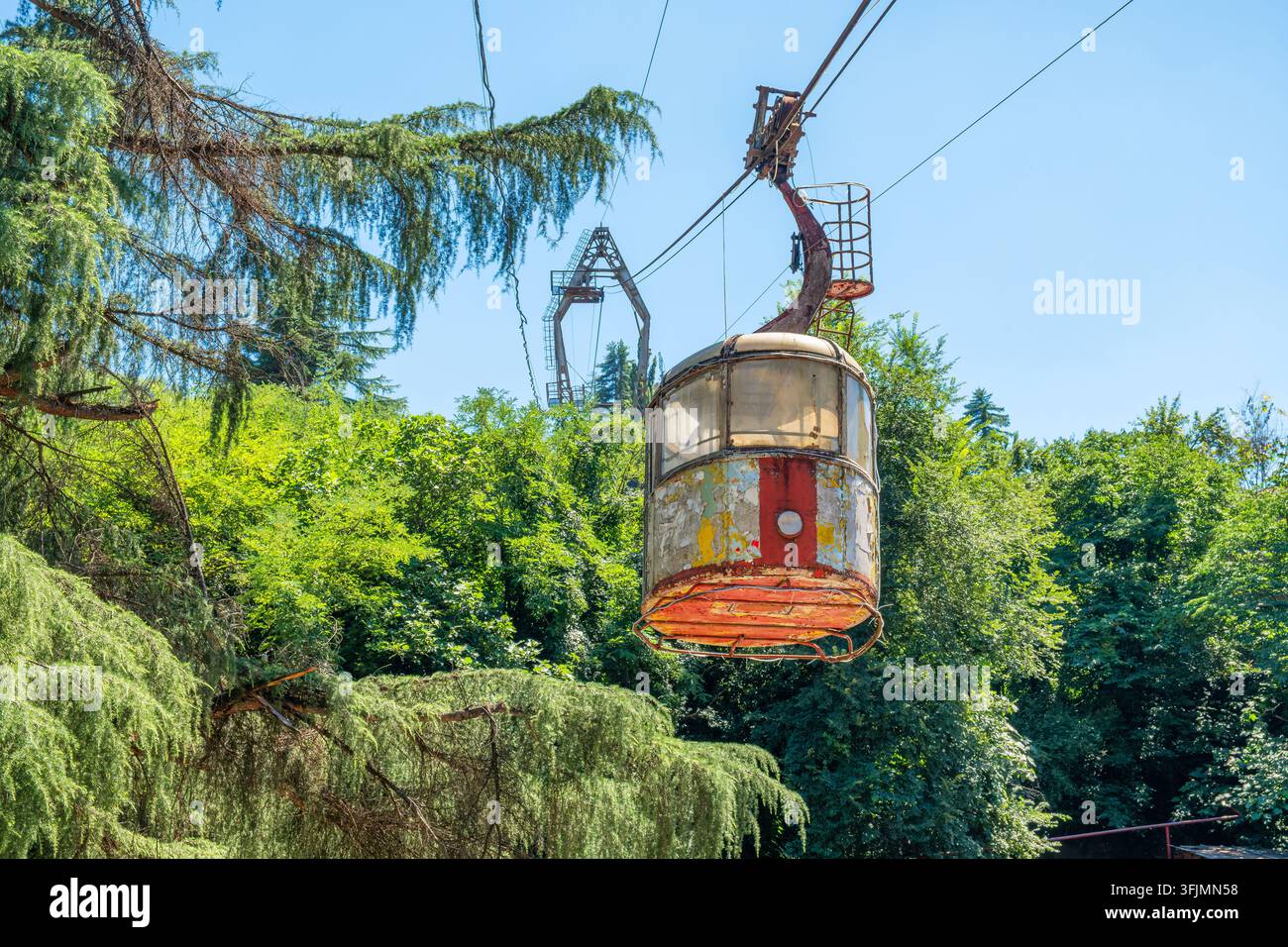 Vecchia cabina di funivia abbandonata sospesa su una funivia dismessa nella città di Chiatura, Georgia. Infrastruttura sovietica, eredità industriale, decadenza urbana Foto Stock