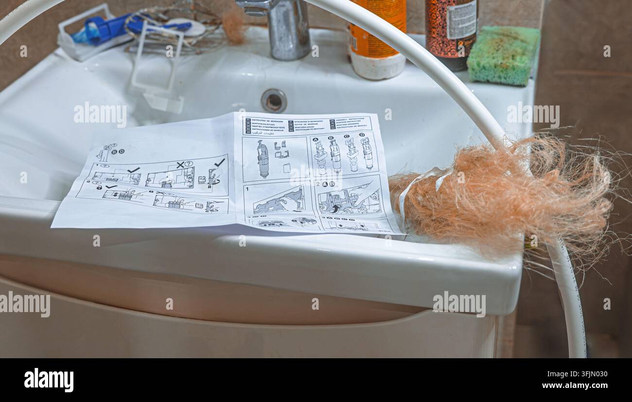 Installazione di uno scaldabagno in una doccia con materiali idraulici e un manuale di installazione sul lavandino del bagno Foto Stock