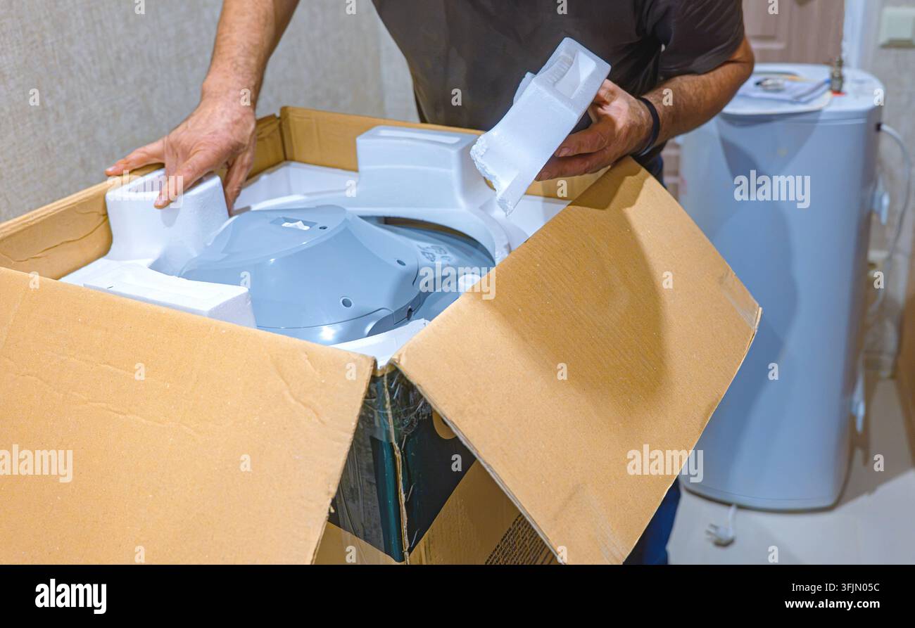 Nuovo scaldabagno elettrico che viene disimballato da un idraulico per la sostituzione e l'installazione in una casa Foto Stock