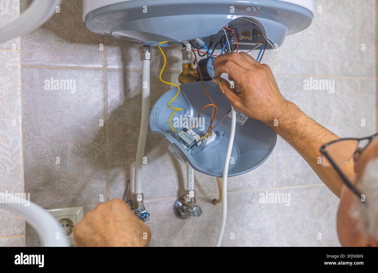 Idraulico che monta una valvola di scarico e componenti interni in un serbatoio di WC incorporato Foto Stock