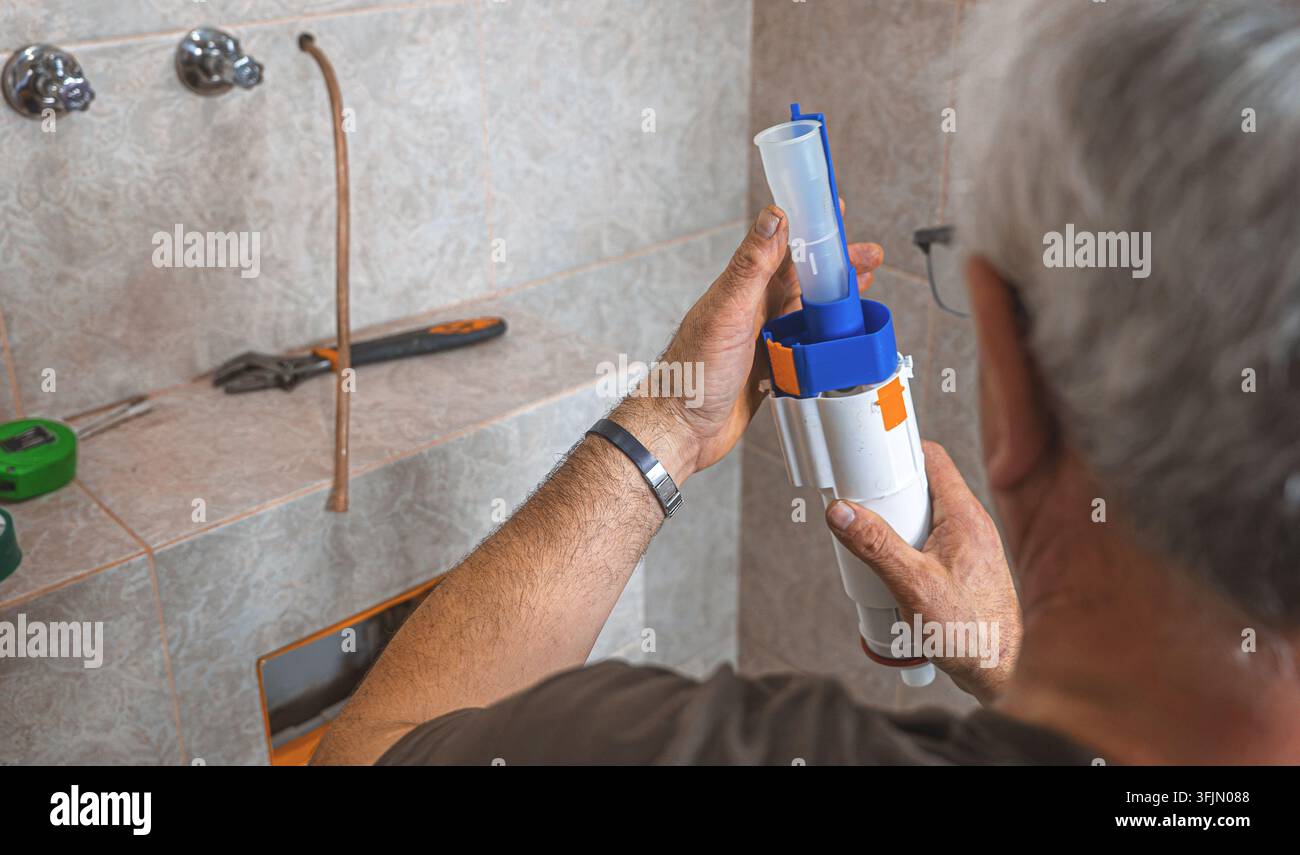 Idraulico che monta un meccanismo di scarico interno in un serbatoio di toilette nascosto Foto Stock