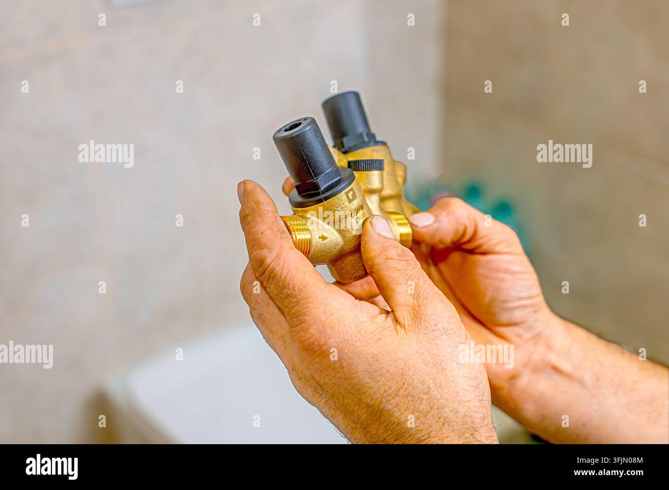 Idraulico che monta un riduttore di pressione originale su uno scaldabagno domestico durante lavori di idraulica Foto Stock