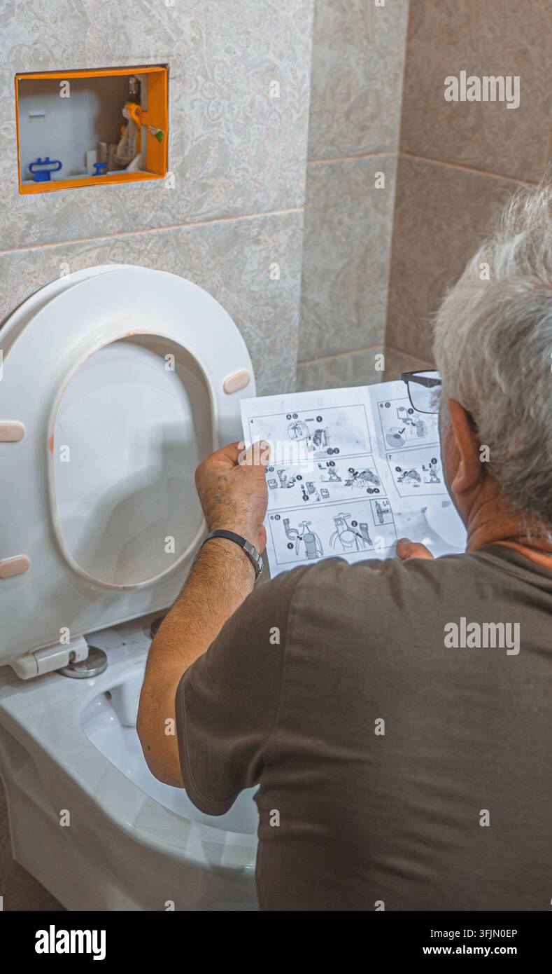 Idraulico che lavora sul meccanismo interno di una cisterna di toilette nascosta Foto Stock