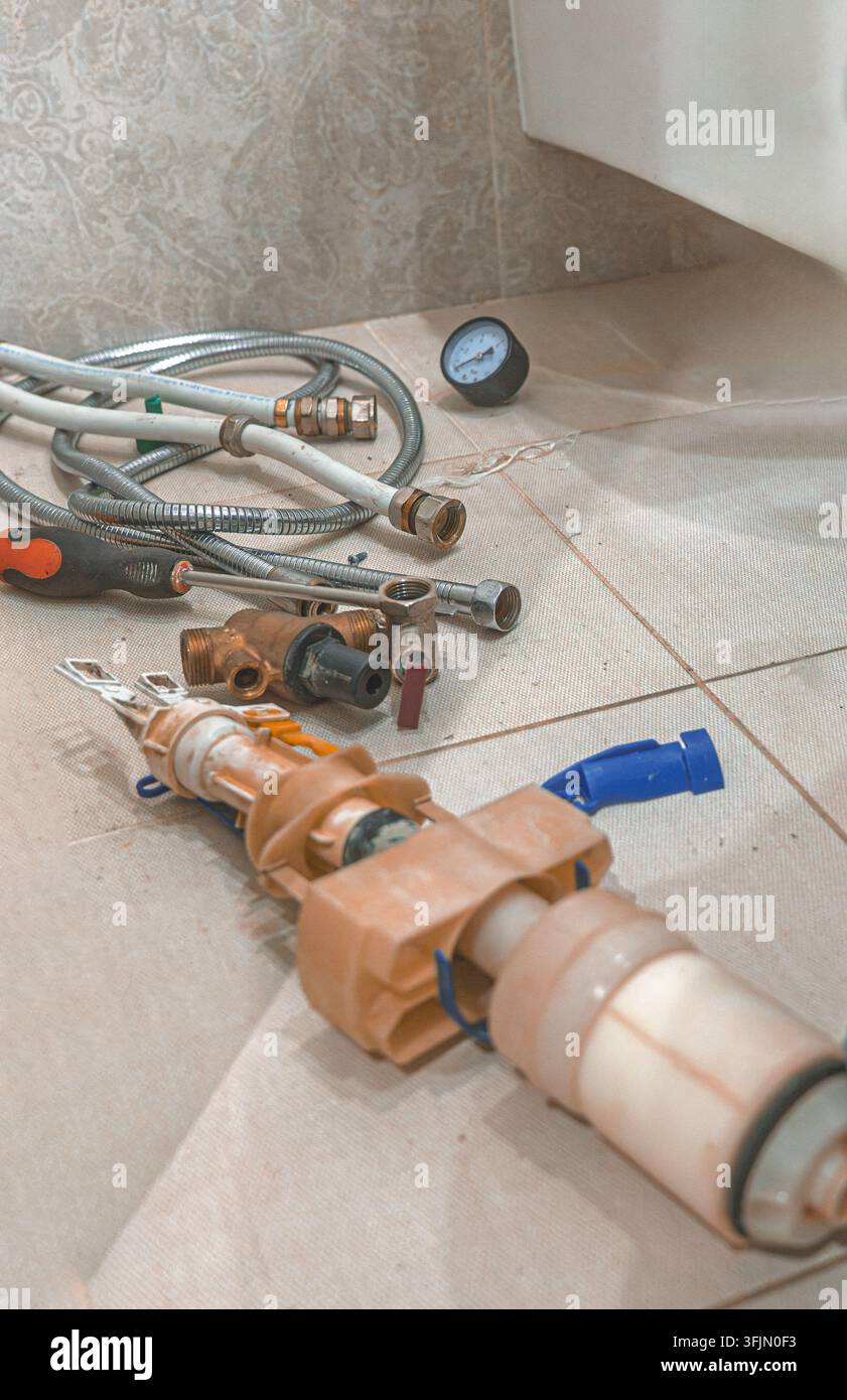 Rifiuti idraulici e materiali usati dopo l'installazione della caldaia con valvola riduttrice di pressione in fibra di canapa per tubi in plastica e Foto Stock