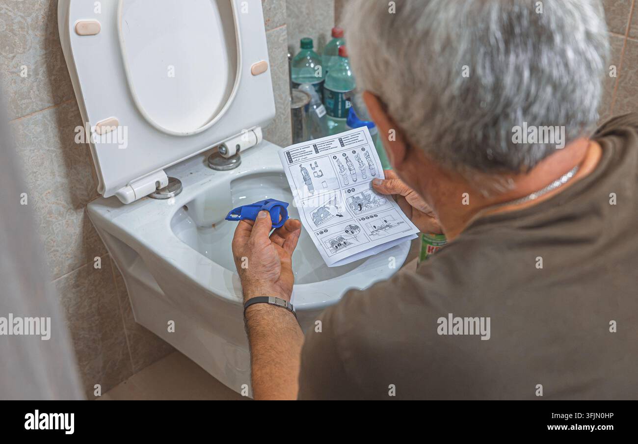 Idraulico professionista che regola un meccanismo di scarico interno all'interno di una cisterna nascosta Foto Stock