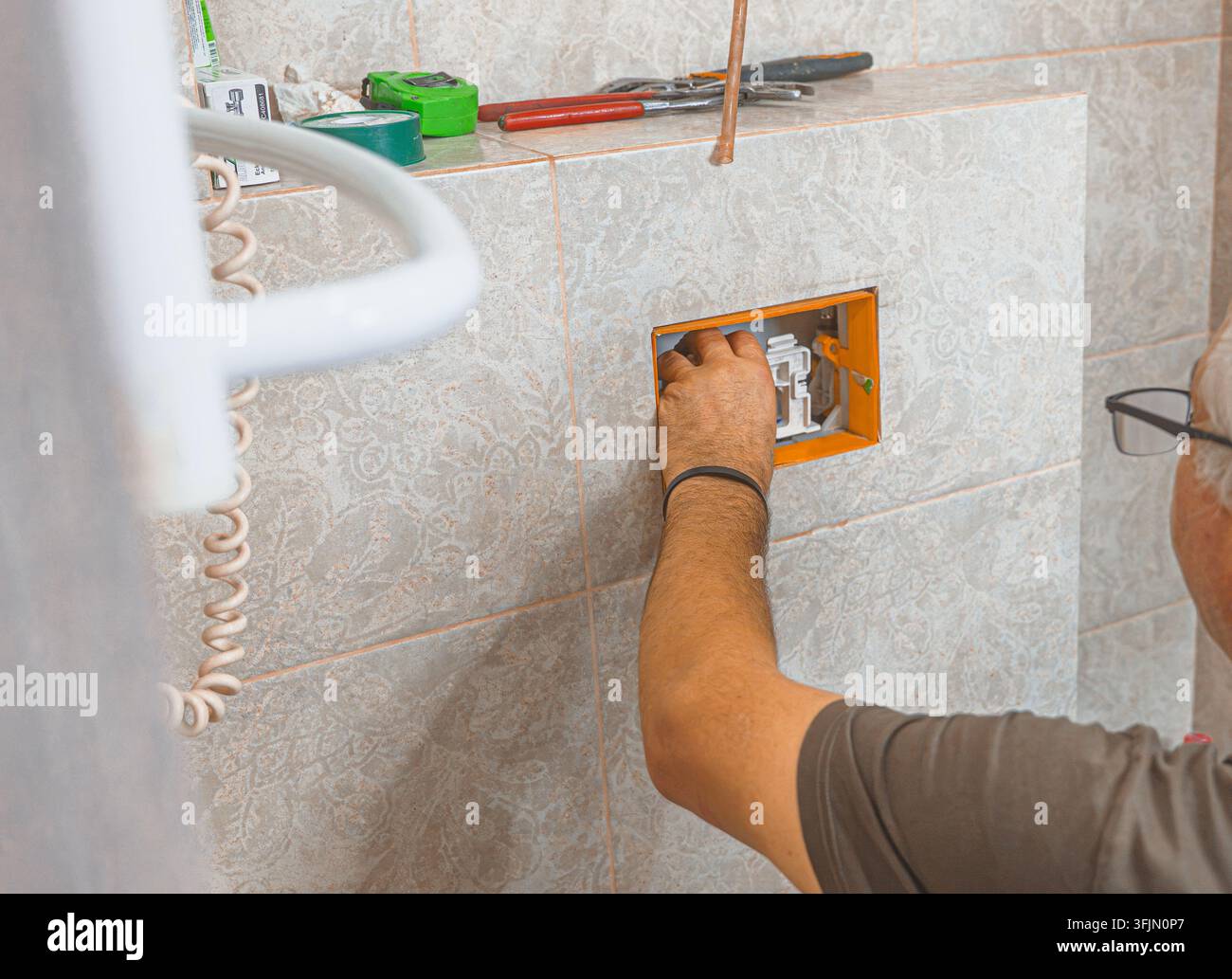 Idraulico professionista che monta e regola i componenti interni della cassetta di risciacquo del water Foto Stock