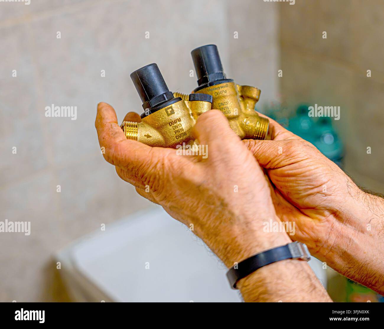 Idraulico professionista che installa un riduttore di pressione originale su uno scaldabagno elettrico domestico durante lavori di manutenzione e installazione idraulica Foto Stock