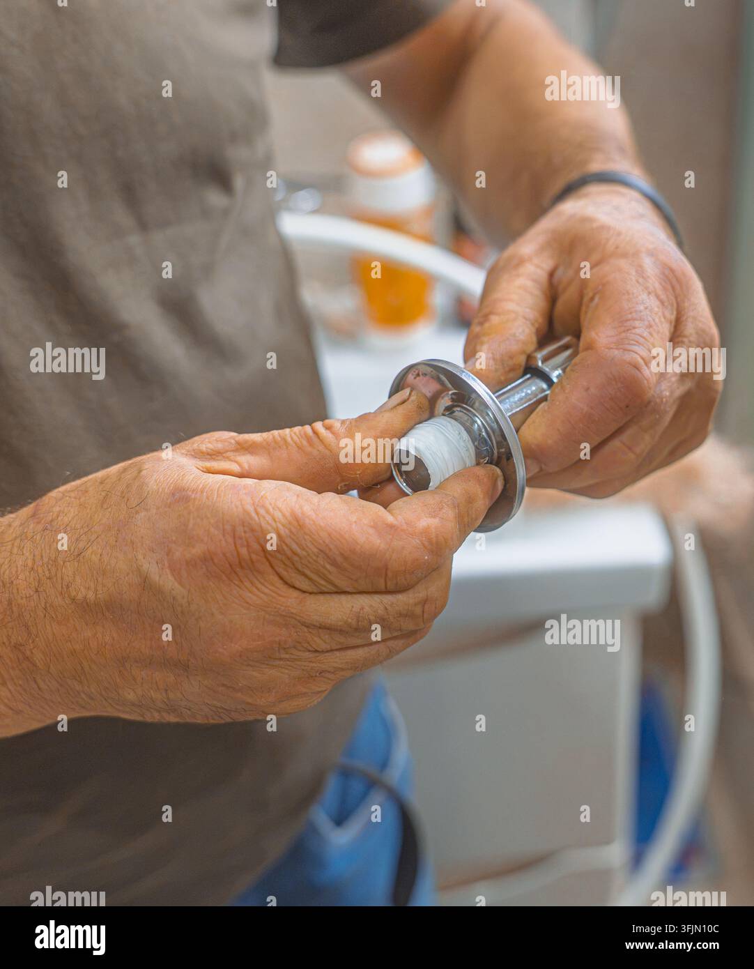 Idraulico professionista che avvolge del nastro PTFE intorno a una filettatura del tubo per una tubazione sicura Foto Stock