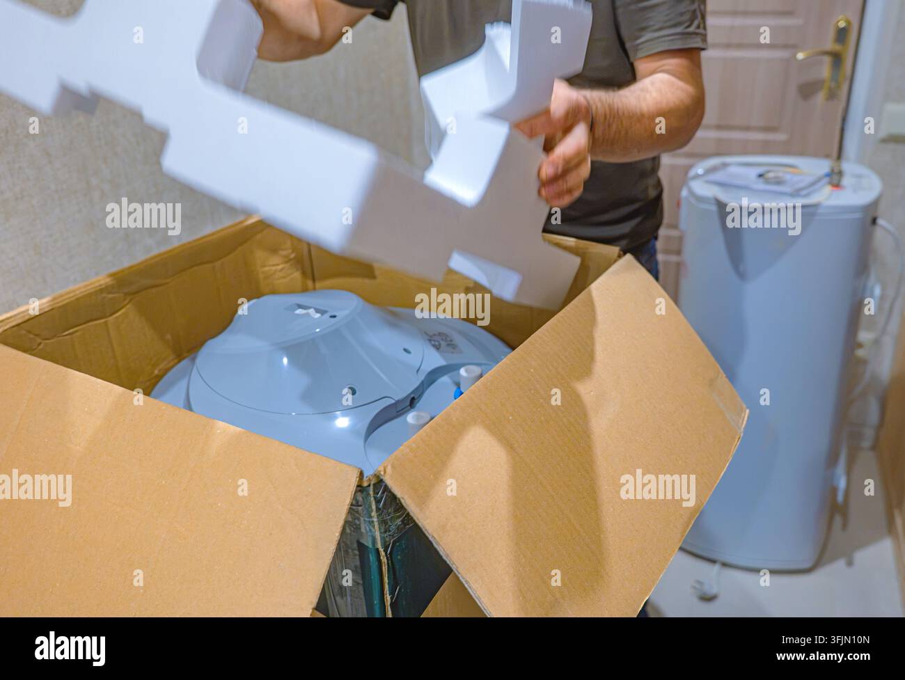 Svuotare un nuovo scaldabagno elettrico per l'installazione dopo la rimozione di un vecchio elettrodomestico Foto Stock