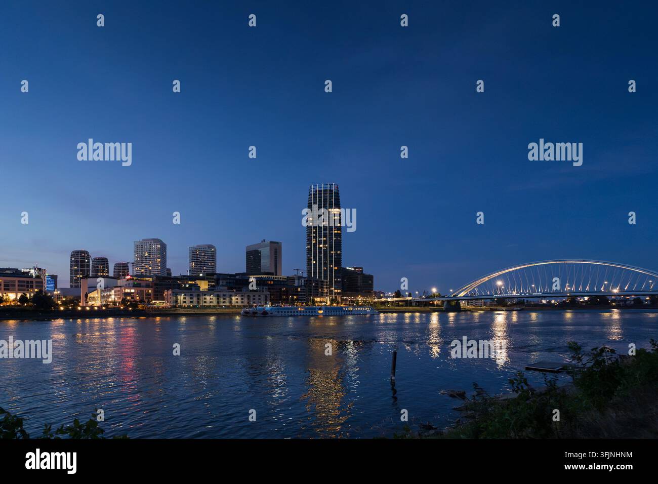 Silhouette moderna illuminata della città e ponte ad arco sul fiume Danubio al crepuscolo a Bratislava. Foto Stock