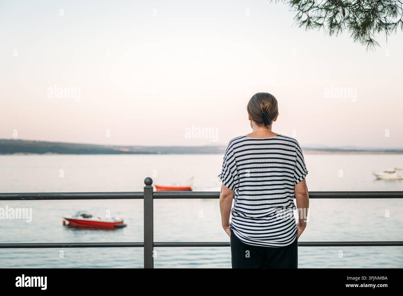 Donna in piedi sulla riva dell'oceano tranquillo durante il crepuscolo mattutino. Concetto di mindfulness pacifica, fuga al mare e momento di viaggio tranquillo Foto Stock
