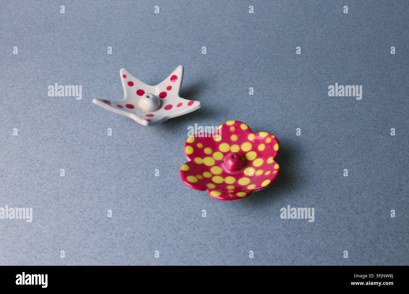 Due portaincenso in ceramica giocosi, con una stella bianca e un fiore rosso a pois, aggiungono un tocco vivace a qualsiasi arredamento domestico o spazio di relax Foto Stock