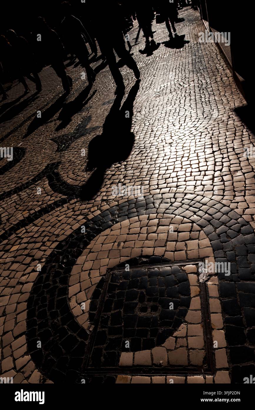 Ombre umane fugaci sui motivi di pietra calcada storici portoghesi (Porto, Portogallo: 23-dic-2024) Foto Stock