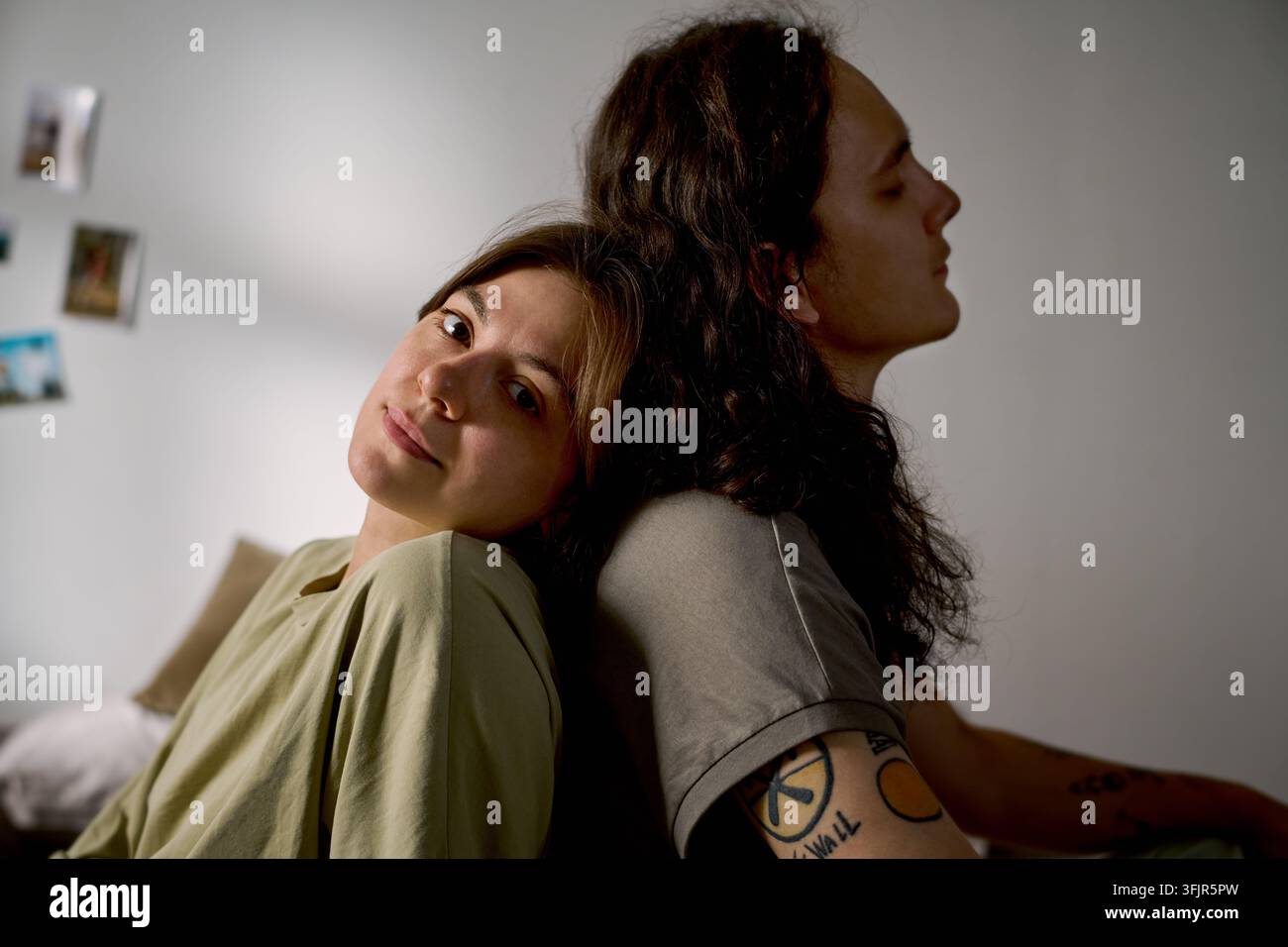 Ritratto di una coppia romantica seduta schiena contro schiena a casa Foto Stock
