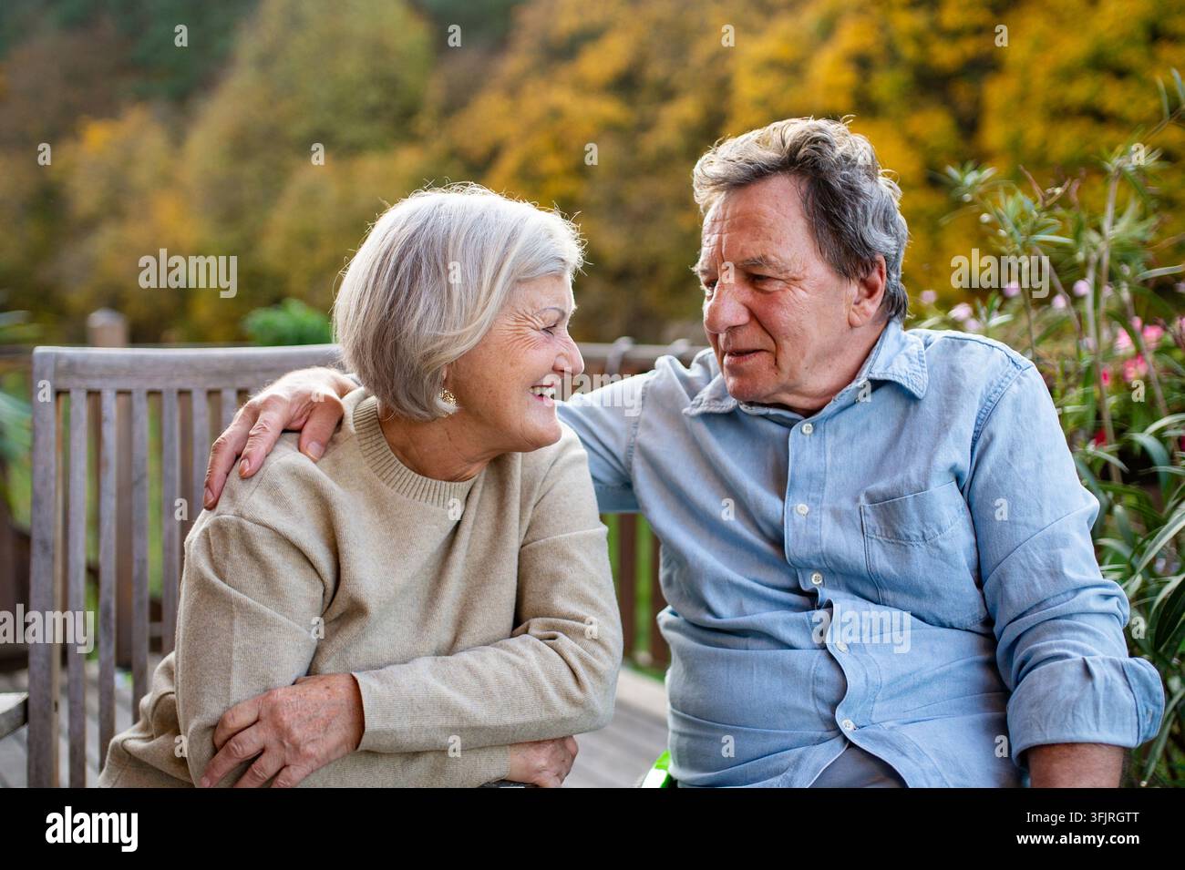 Un momento tranquillo per una coppia senior, godendosi una calda serata autunnale in terrazza. Foto Stock