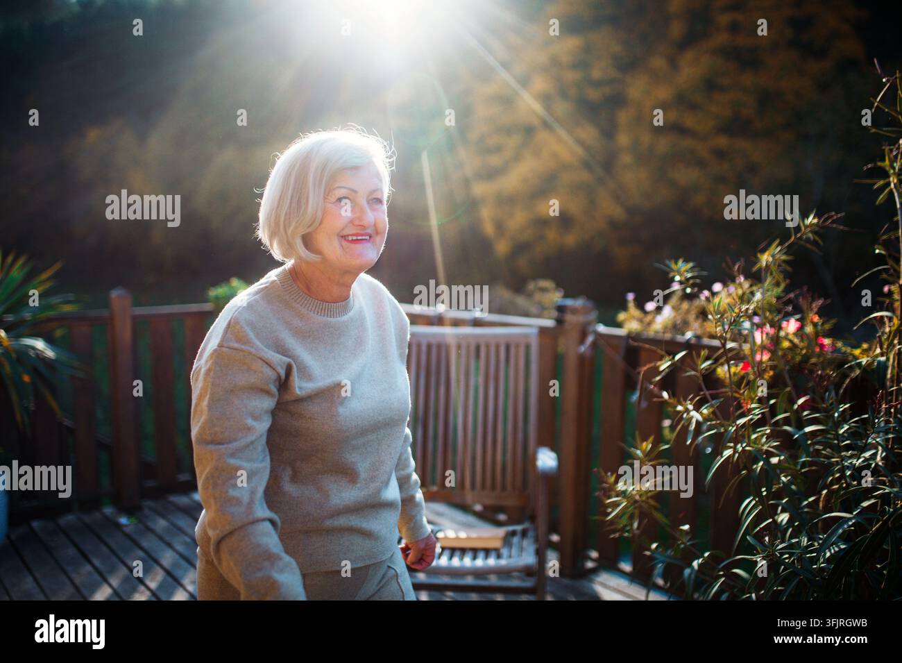 Donna anziana che gode del caldo sole autunnale. Foto Stock