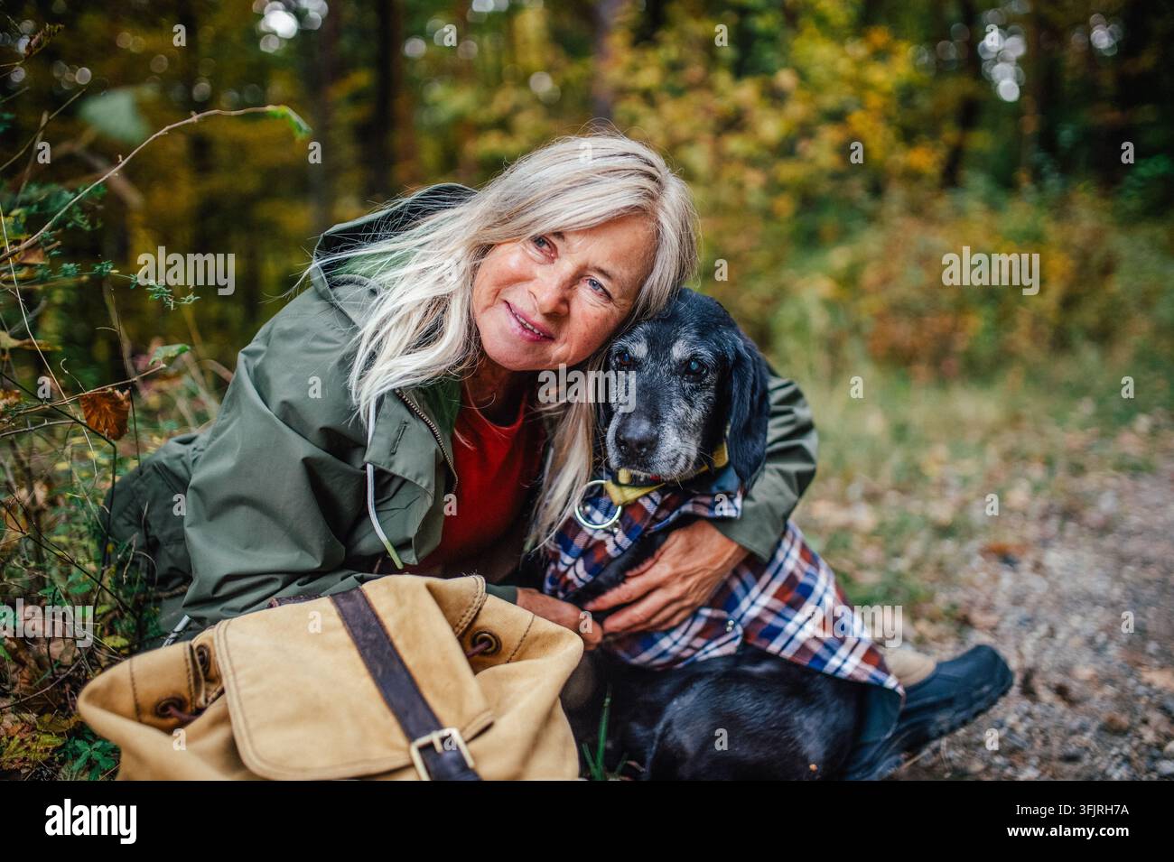 Amata proprietaria di cani che abbraccia il suo animale domestico durante una tranquilla passeggiata autunnale. Foto Stock