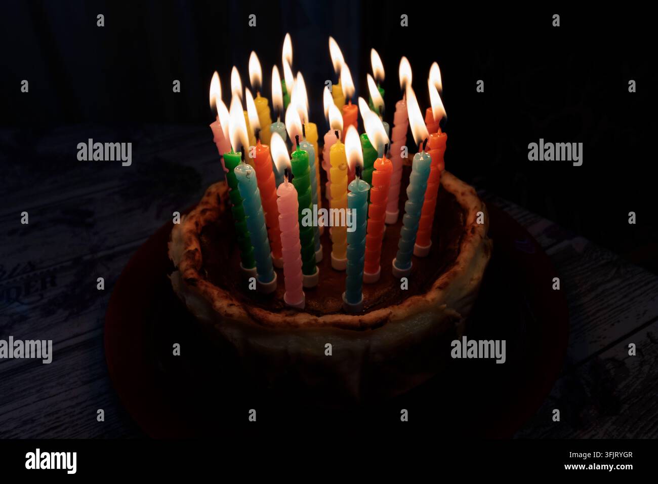 Torta di compleanno al buio con candele accese in un'atmosfera misteriosa Foto Stock