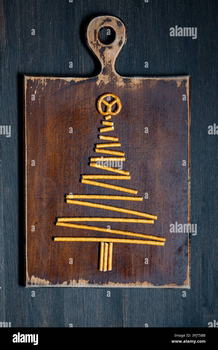 Albero di Natale fatto di bastoncini di pretzel su tavola di legno, vista dall'alto. Silhouette creativa di albero di Natale disposta con bastoncini di pretzel salati e una torsione su un Foto Stock