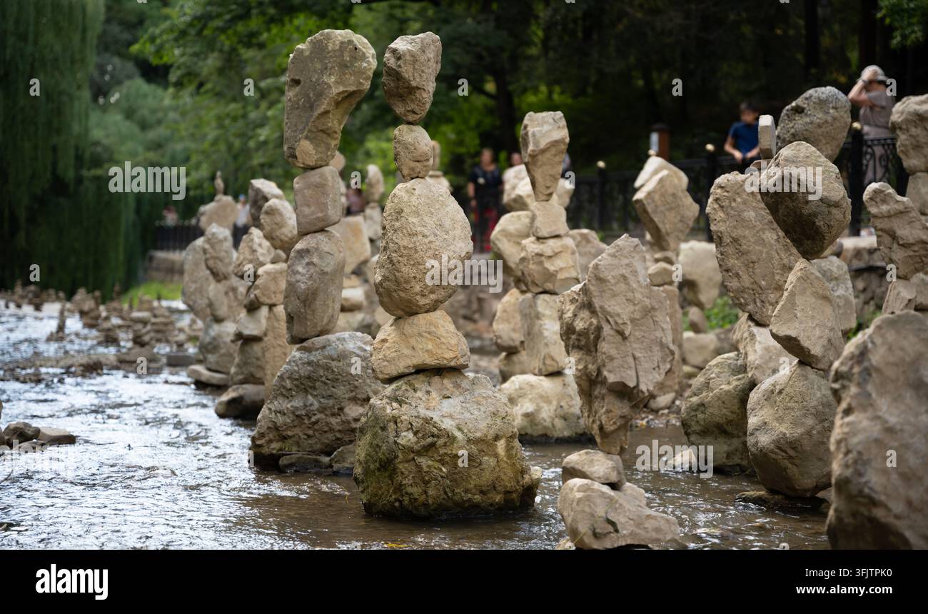 Una fotografia che mostra diverse pile di rocce bilanciate in piedi in un ruscello poco profondo e fluente. Le pietre ruvide e chiare sono disposte con cura Foto Stock