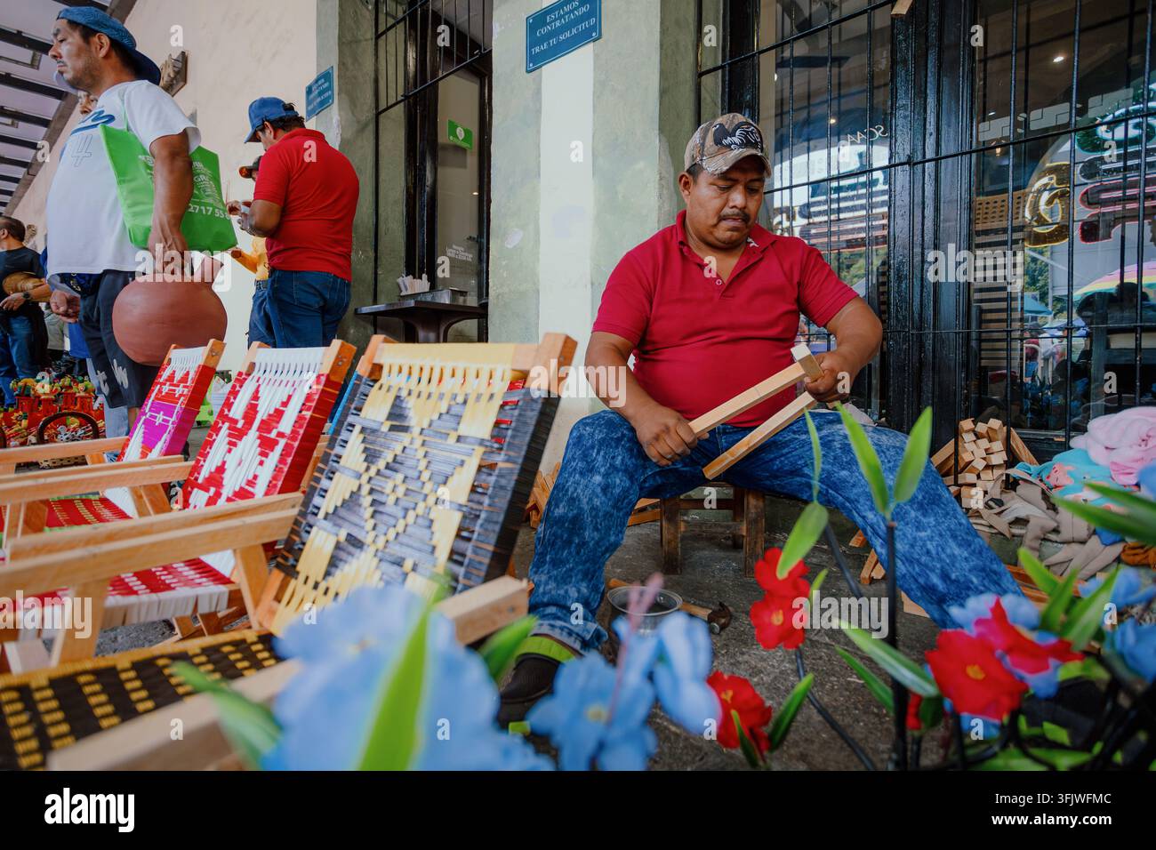 Un artigiano lavora su sedie in legno fatte a mano con sedili intrecciati alla fiera tradizionale del baratto a San Pedro Cholula, Messico, l'8 settembre 2026. Foto Stock