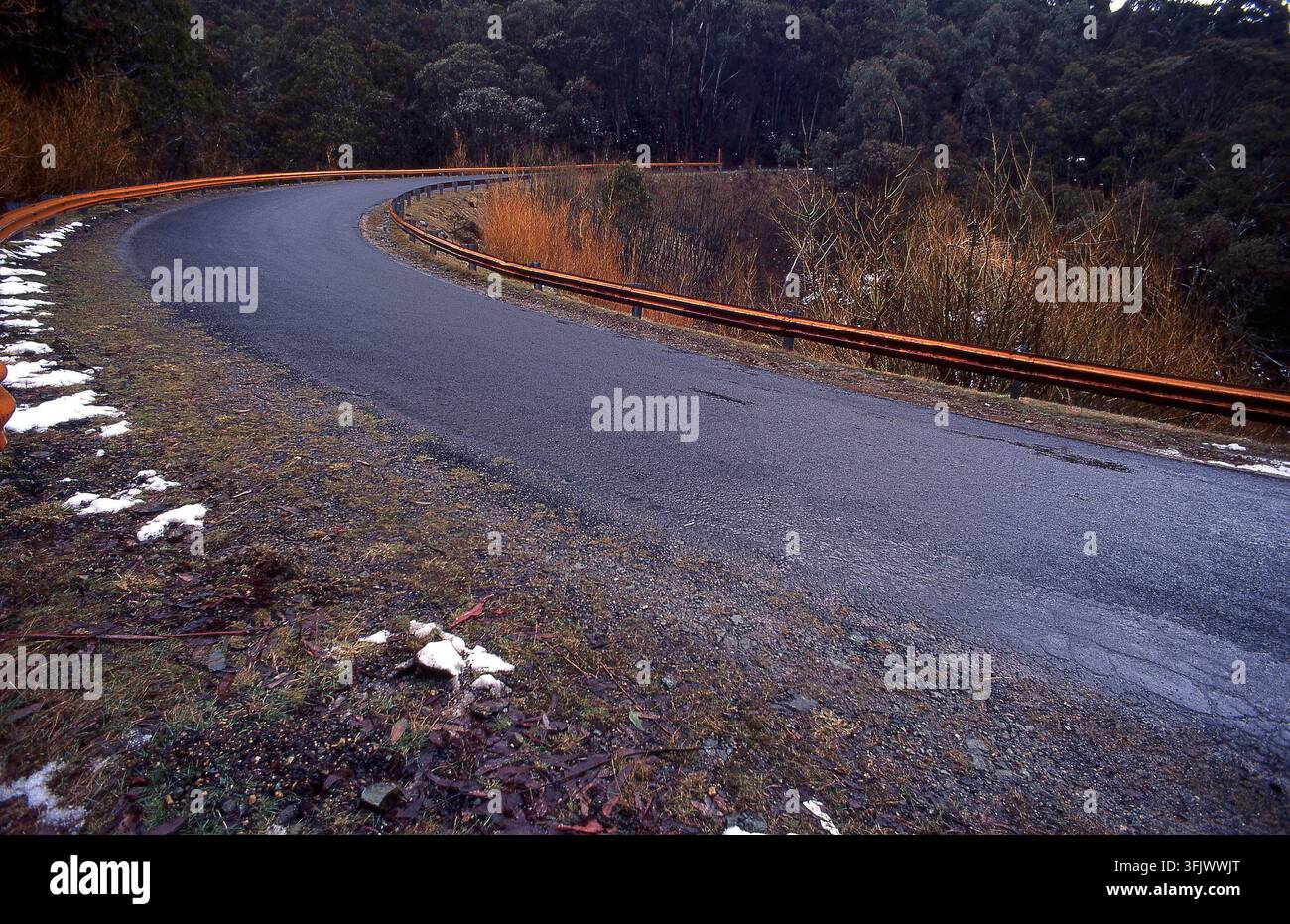 Condizioni di guida pericolose su una strada tortuosa e ghiacciata dopo una nevicata in una zona boschiva remota del New South Wales, Australia. Foto Stock