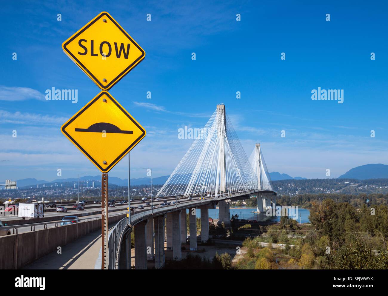 Segni di avvertimento gialli per il traffico lento e i dossi stradali accanto al ponte a cavi sospesi Port Mann Bridge sul fiume Fraser a Surrey British Columbia Canada. Foto Stock