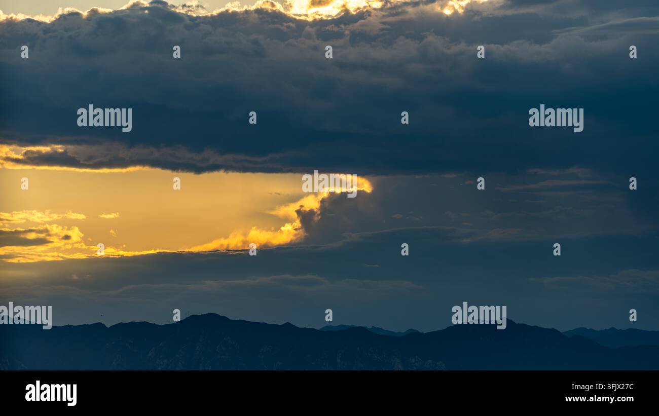 Nuvole scure e pesanti che si aprono per rivelare un tramonto dorato nel distretto di Haidian, Pechino Foto Stock