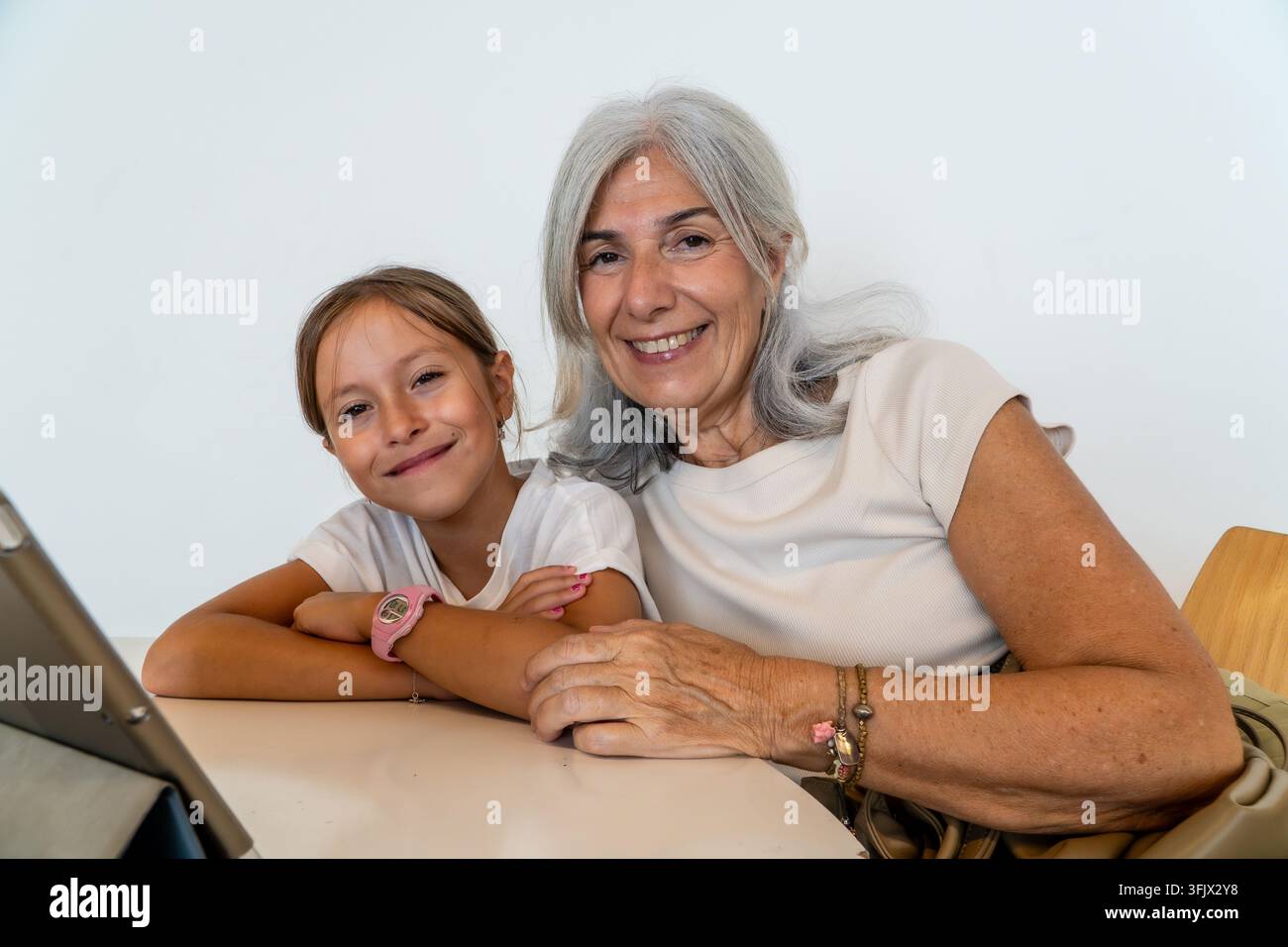 Nonna e nipote che si legano, sorridendo, usando un tablet digitale Foto Stock