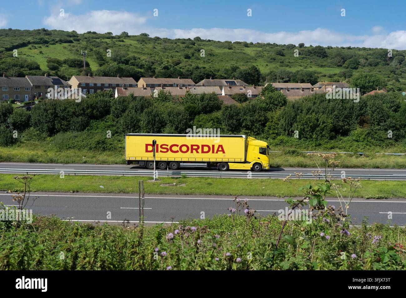 Un camion merci Discordia giallo procede lungo la A20 vicino a Folkestone, nel Kent, trasportando merci sotto i North Downs. Foto Stock