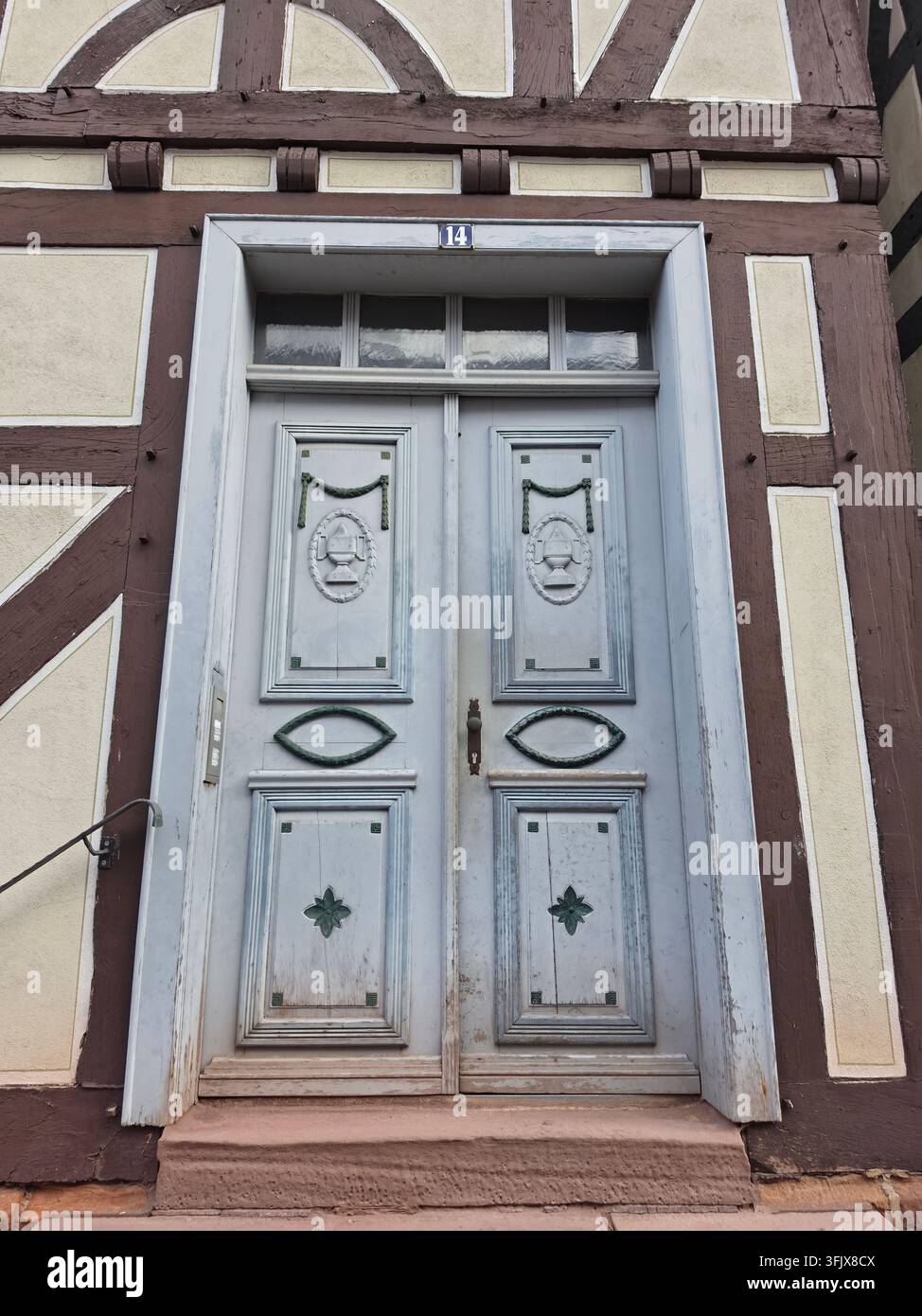 Antica porta doppia in legno blu chiaro consumata, ingresso di una casa a graticcio storica con dettagli architettonici tradizionali e finestra a timpano. - Immagine stock catturata con smartphone