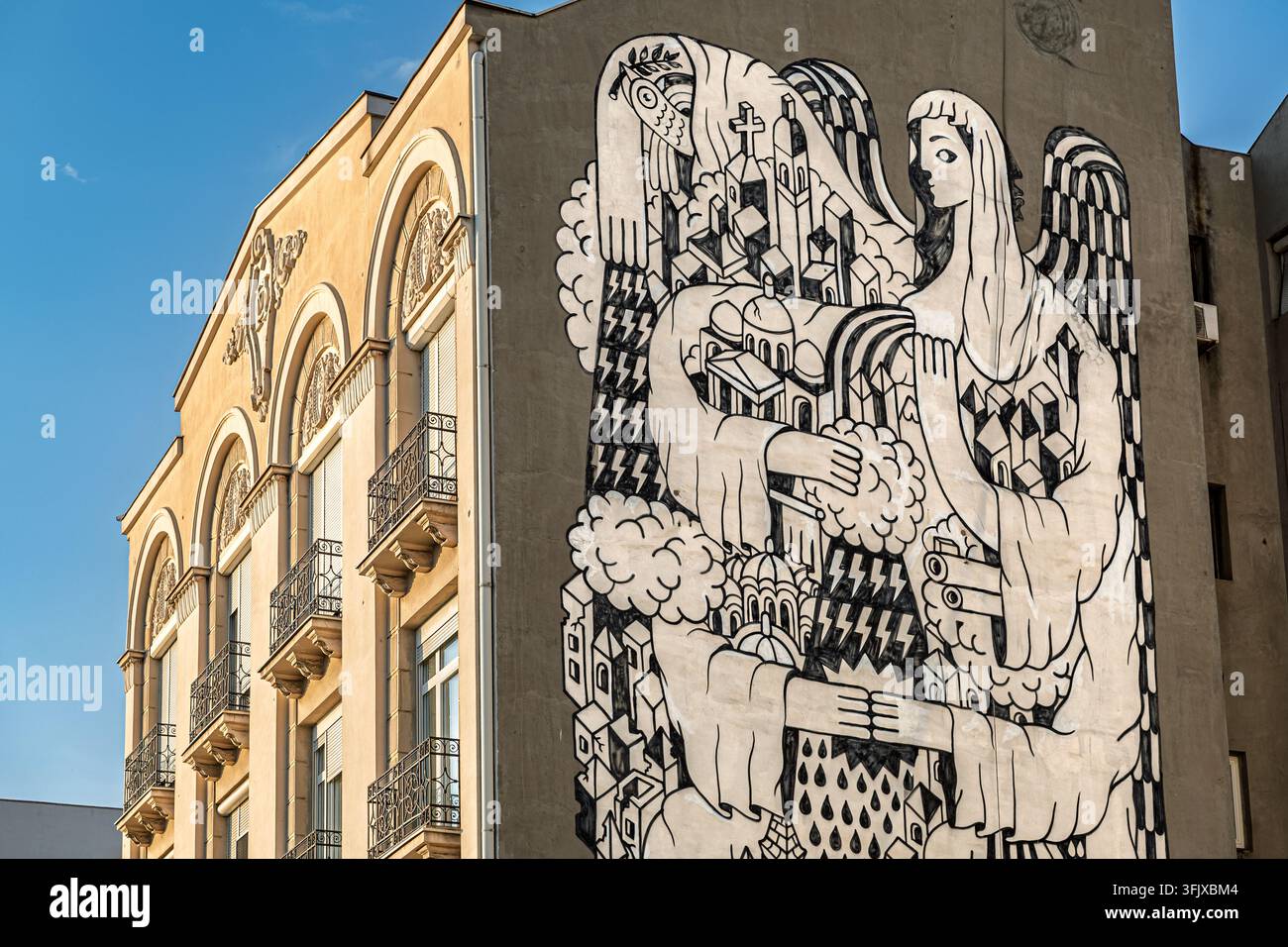 Un grande murale monocromo che raffigura una figura di angelo custode che sorveglia una città dipinta su un muro di un edificio urbano, via Karadordeva, Belgrado, Serbia Foto Stock