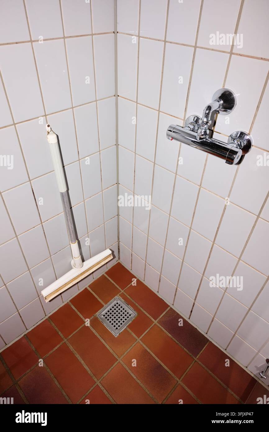 Primo piano di uno scarico della doccia e di un tergi per pulire l'acqua. Manutenzione della casa e problemi idraulici. Foto Stock
