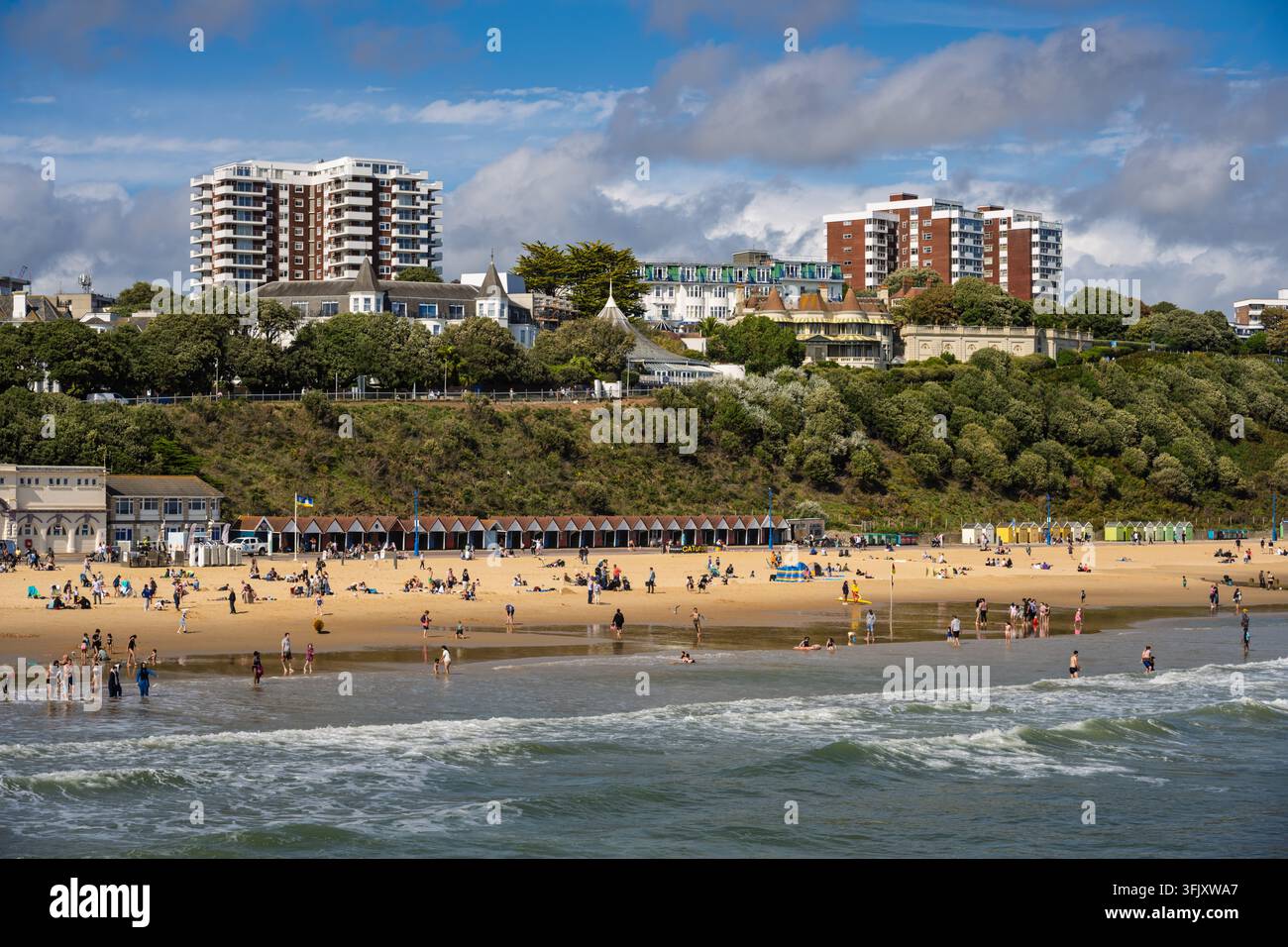 Vista panoramica soleggiata della spiaggia sabbiosa, delle capanne di legno e degli hotel di East Cliff in una vivace giornata estiva a Bournemouth, Dorset, Inghilterra, Regno Unito Foto Stock