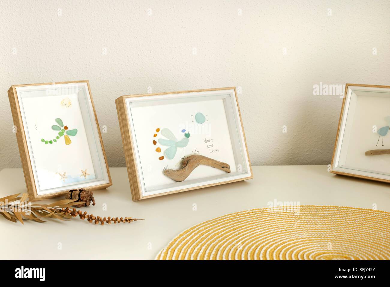 Quadro in vetro di mare con ciottoli incorniciato regalo fatto a mano. Decorazione per la casa libellula pavone artigianato estetico hobby unico. Design di interni arte murale ecologica Foto Stock