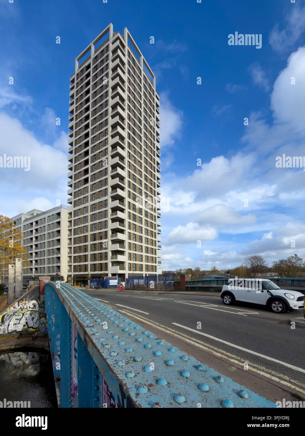 Viaggiare a Londra, una Mini Cooper bianca attraversa il ponte di Scrubs Lane, passando davanti alle torri residenziali moderne dello sviluppo Old Oak. Foto Stock