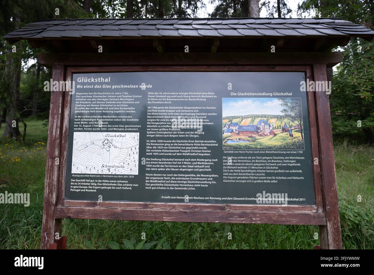 Targa informativa in legno all'aperto su un'antica insediamento vetrario in una foresta verdeggiante e lussureggiante, ideale per uso editoriale sul patrimonio e il turismo. Foto Stock