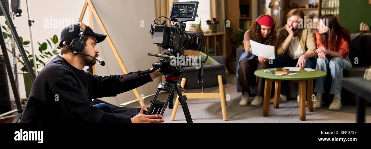 Videomaker che opera una telecamera professionale durante le riprese di un film Foto Stock
