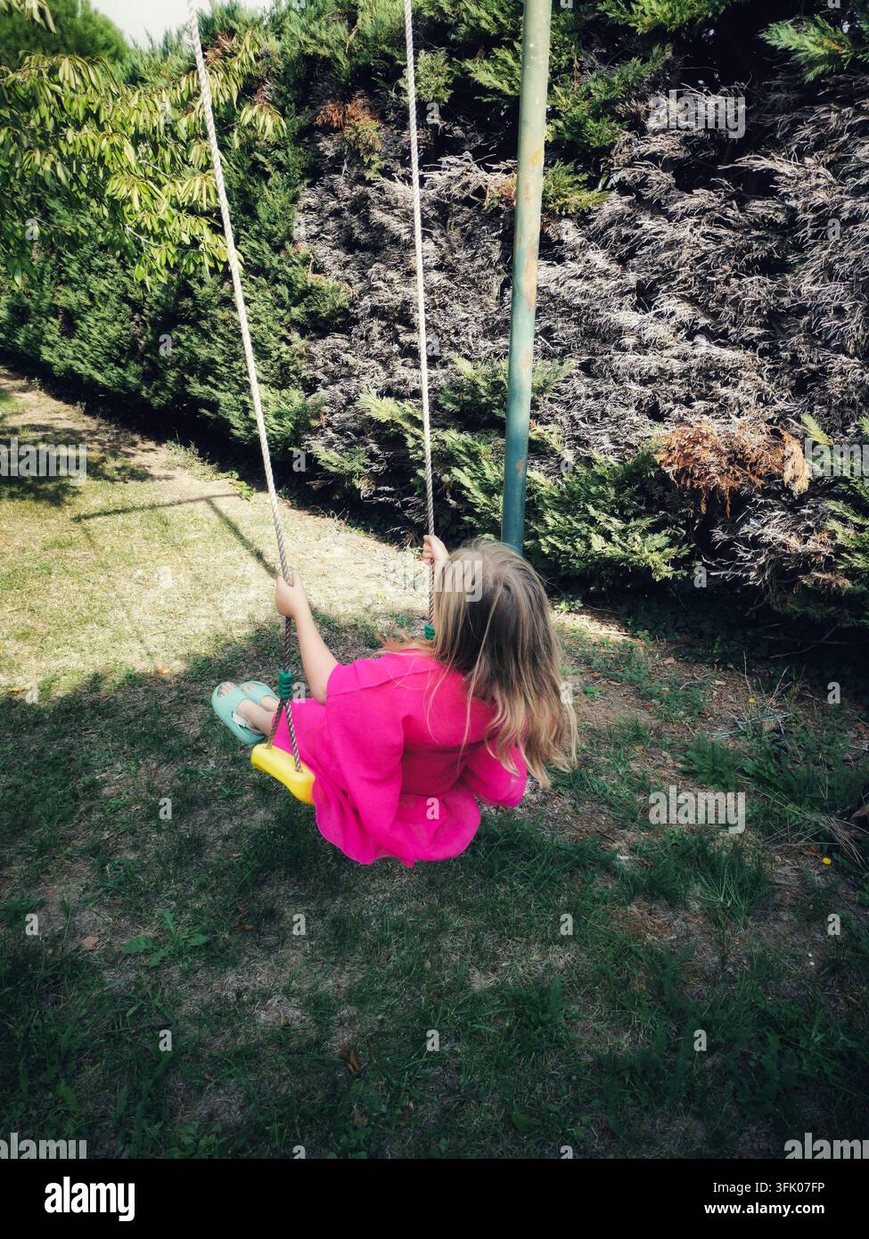 Ragazza che si dondola in un giardino in un pomeriggio soleggiato - Immagine stock catturata con smartphone