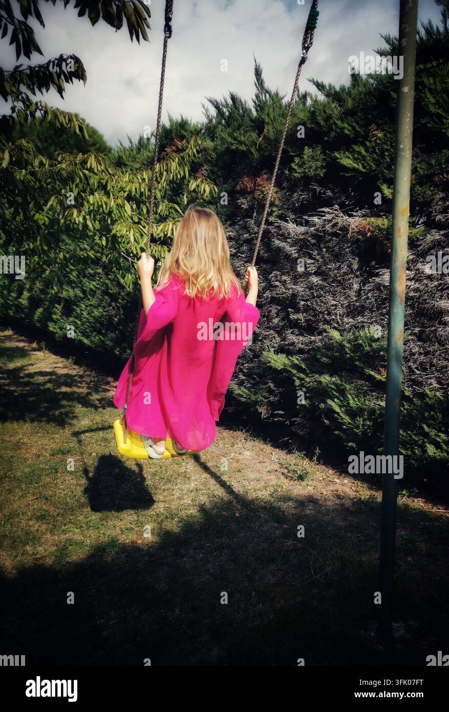 Ragazza che si dondola in un giardino in un pomeriggio soleggiato - Immagine stock catturata con smartphone