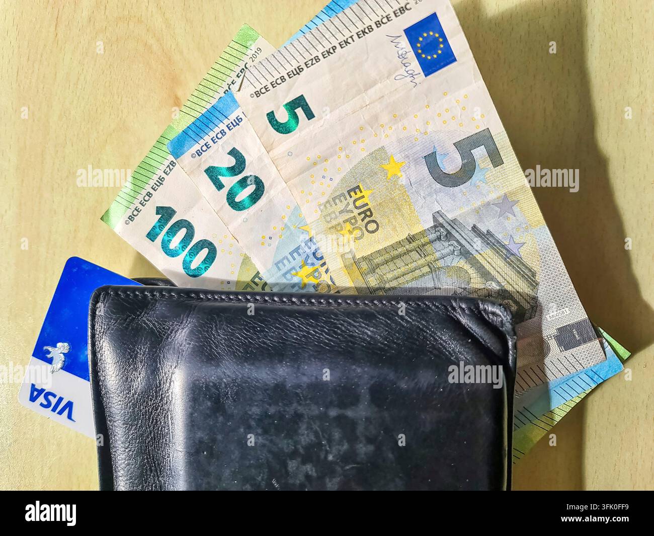 Kiel, Germania - 10. Aprile 2026: Le banconote in euro e la carta di credito VISA sono visibili in un portafoglio nero in pelle su una superficie di legno Foto Stock