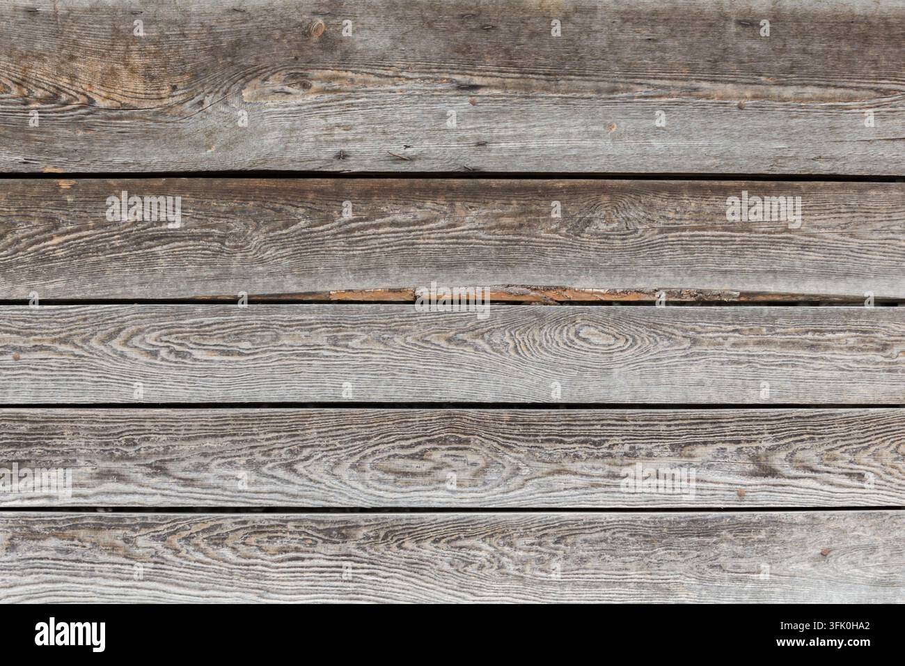 Panneggiate di legno orizzontali consumate dal tempo con venature visibili, nodi e texture superficiale grigio-marrone naturale. Foto Stock