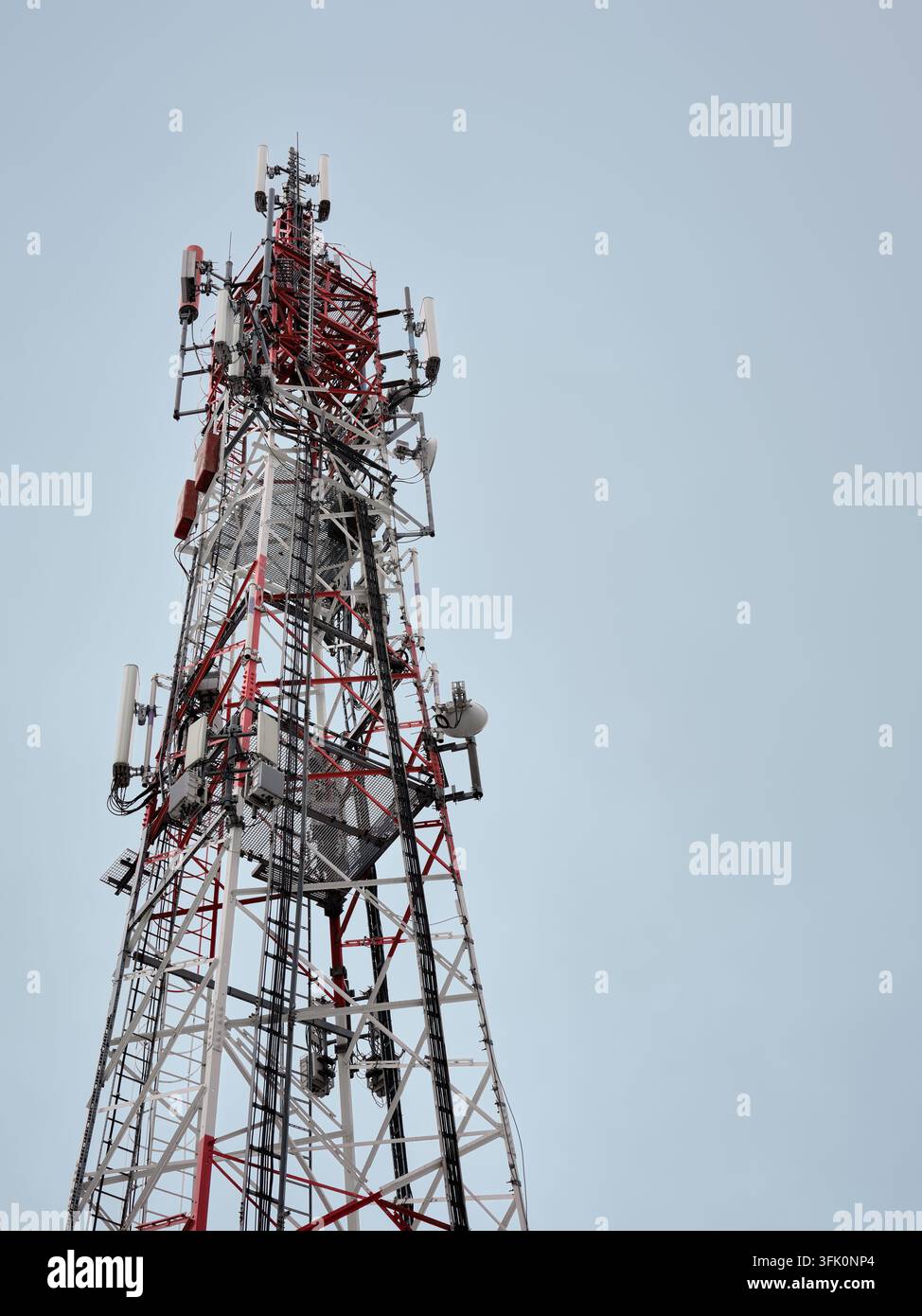 Torre di telecomunicazione con più antenne contro un cielo sereno, che illustra la comunicazione senza fili e l'infrastruttura della rete mobile. Foto Stock