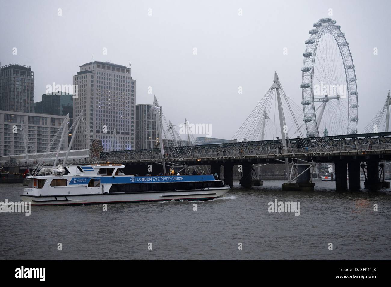 I turisti godono di un giro turistico su una nave River Cruise del London Eye, navigando sul Tamigi a Londra sotto il ponte di Hungerford passando davanti al London Eye Foto Stock